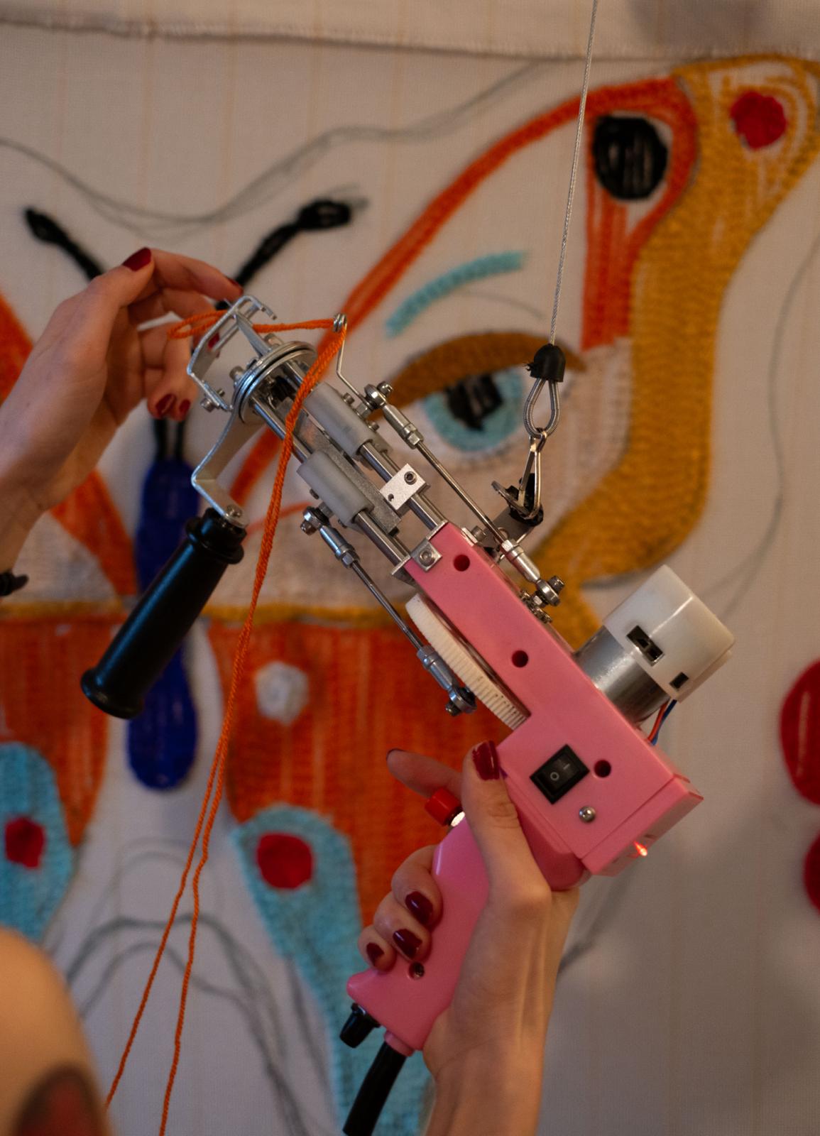 Tufting gun being held in front of a tufting frame 